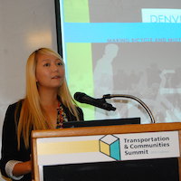 Researcher Jenny Liu stands behind a podium with slides in the background behind her. 