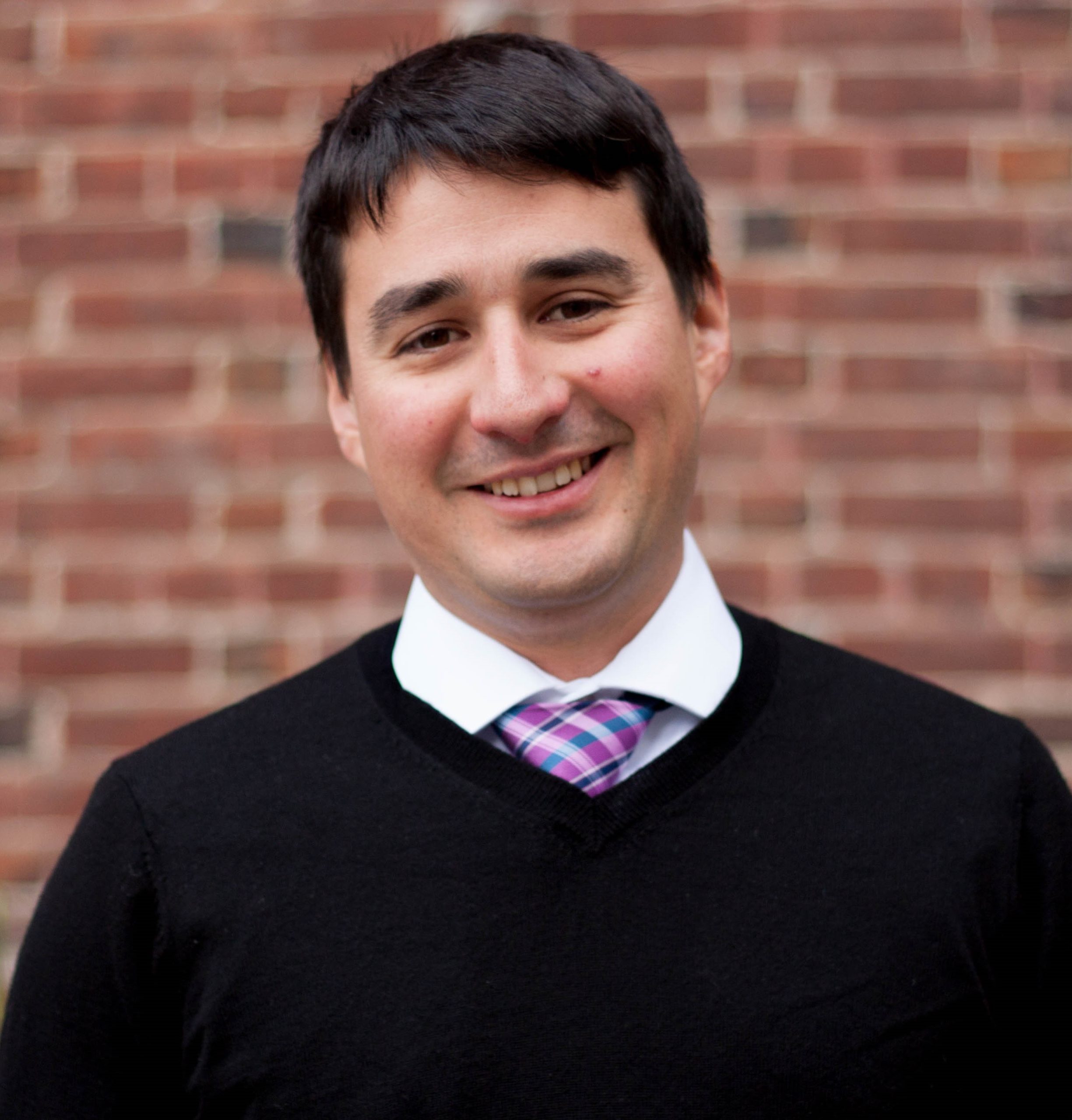 Jesus Barajas with short brown hair, a black shirt and a purple necktie