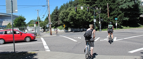 Bicyclists cross an intersection with a bike signal, near a red car
