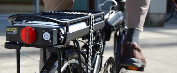 A close-up view of the motor mounted on the back of an e-bike, behind the rider's seat.
