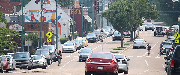 Bicyclists ride past retail establishments