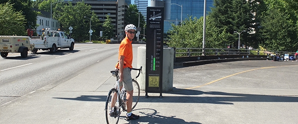 Cyclist stands next to the Hawthorne Bridge Bicycle Counter