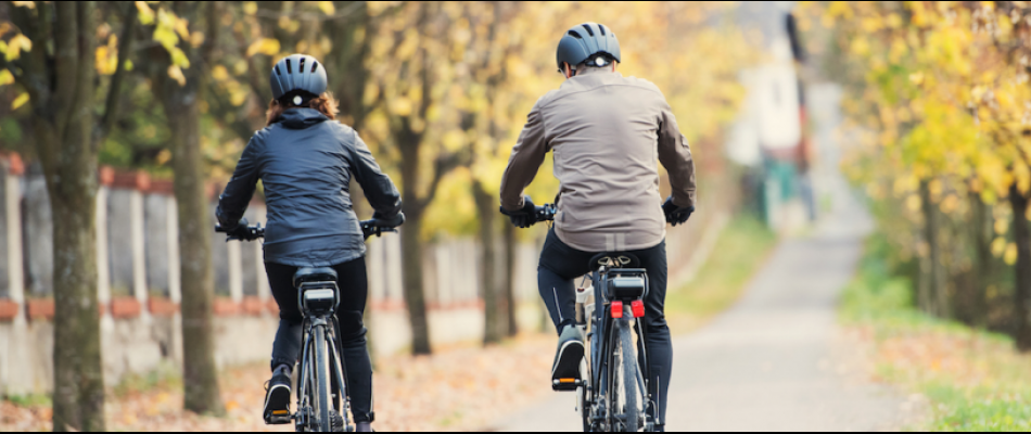 Two people ride e-bikes off into the sunset